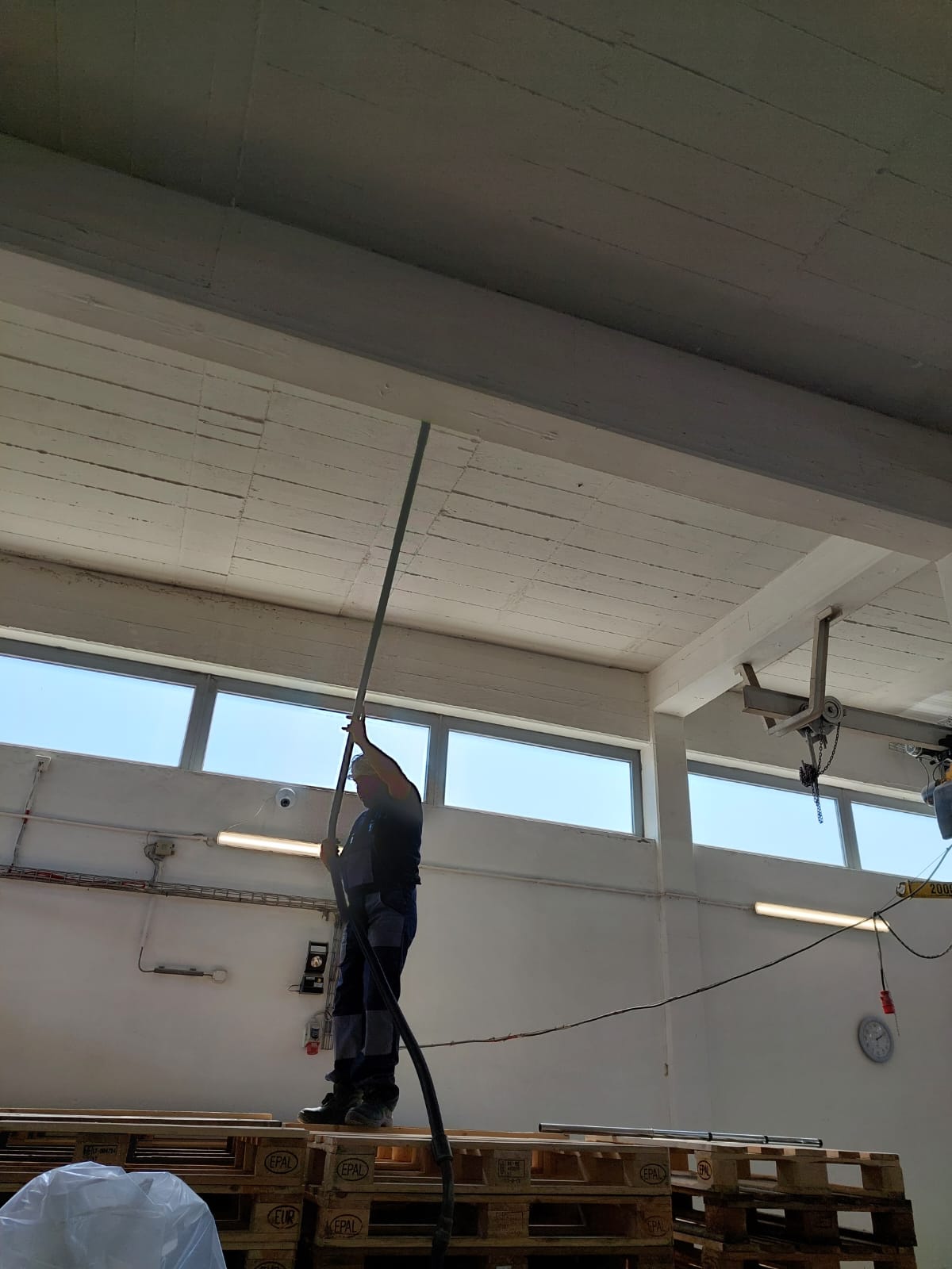 Fachgerechte Deckenreinigung mit Teleskopstange in einer Industriehalle