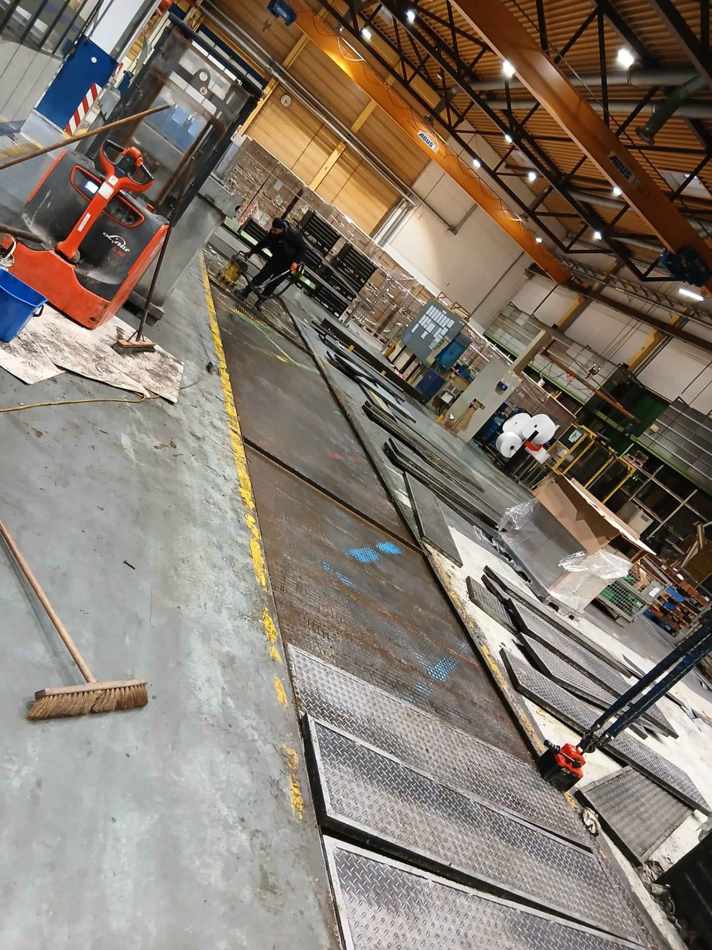Demontage langer Stahlplatten und Schwerlastböden in einer Produktionshalle